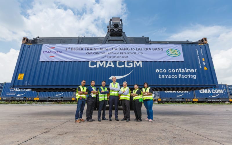 Des employés de CMA CGM faisant une photo devant un conteneur en Thaïlande. 
