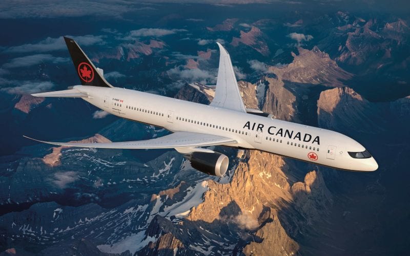 Avion de la compagnie air canada volant au dessus de montages enneigées 