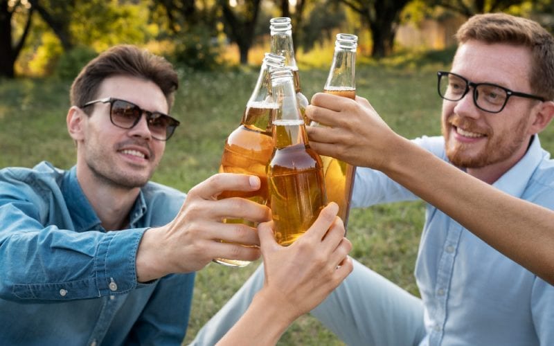 Deux hommes, et leurs amis, buvant des bières dans un parc en Allemagne. 