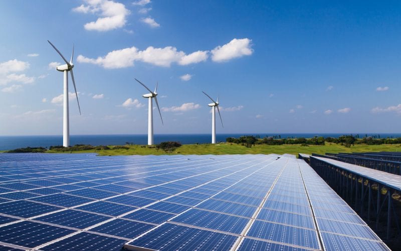 Trois éoliennes et des panneaux solaires. 