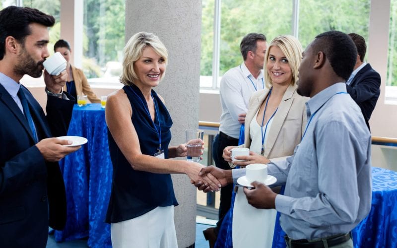 Un évènement de networking entre professionnels avec notamment une femme serrant la main à un homme. 