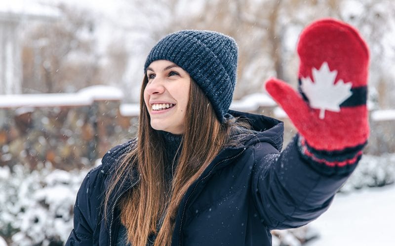 Femme sous la neige avec bonnet et un gant rouge et blanc. 