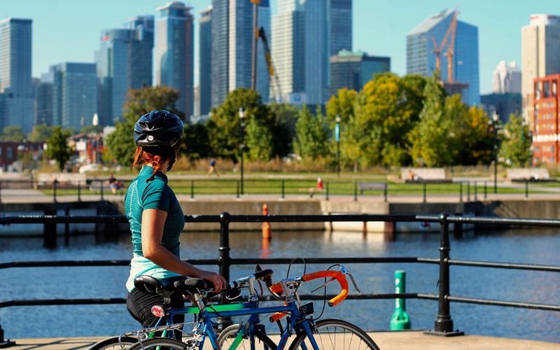 Une femme au Canada en train de faire du vélo sous le soleil en ville. 