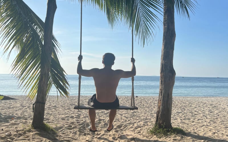 Une homme sur une balançoire sur une plage thaïlandaise. 