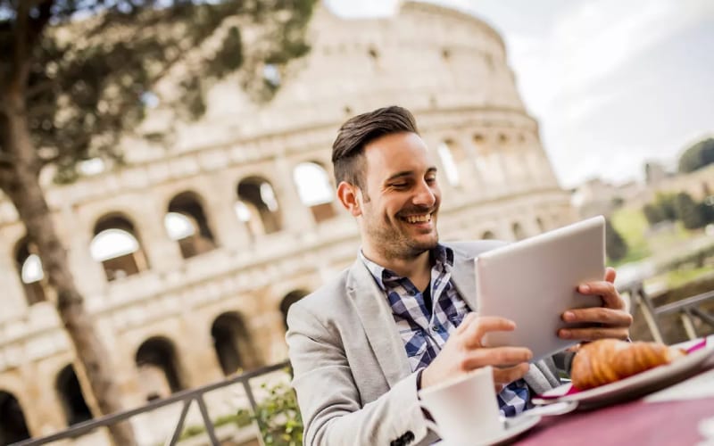 Un homme travaillant et souriant devant le Colisée en Italie. 