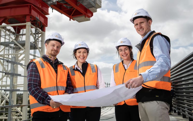 Quatre ingénieurs sur un chantier au Canada avec un plan pour les travaux. 