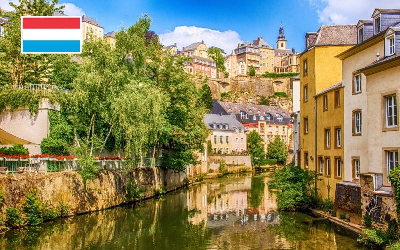 Ville ensoleillée de Luxembourg avec rivière au centre.